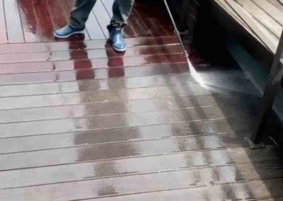 employee cleaning a composite wood deck with soft wash power washing in Monmouth County, NJ