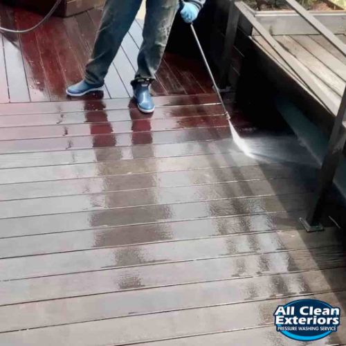 employee cleaning a composite wood deck with soft wash power washing in Monmouth County, NJ