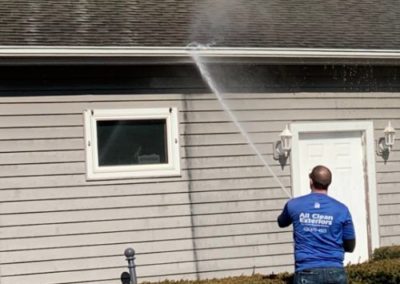 employee power washing a gutter with soft wash pressure in Shrewsbury, NJ