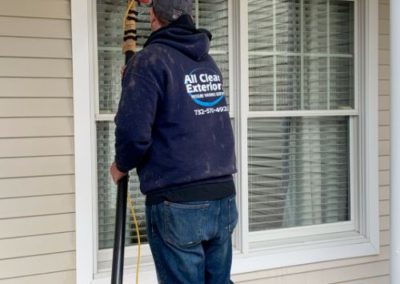employee cleaning a residential window in Rumson, NJ