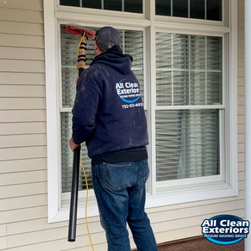 employee cleaning a residential window in Rumson, NJ