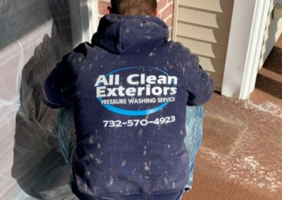 employee taping plastic sheet to cover and protect a door prior to power washing in Rumson, NJ